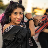 一群西班牙裔青少年跳嘻哈的照片，焦点是一个带着淘气微笑的女性